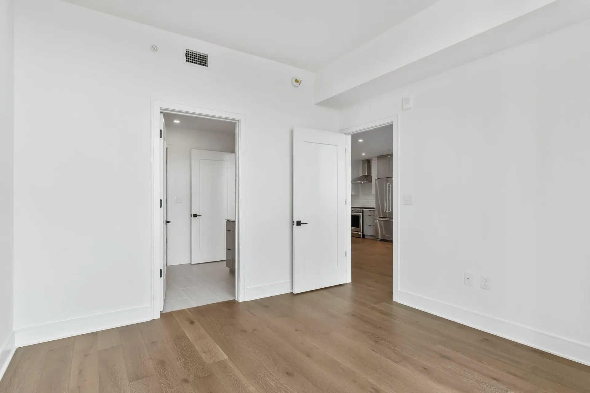 Interior view of a modern apartment, showcasing wood floors and white walls.