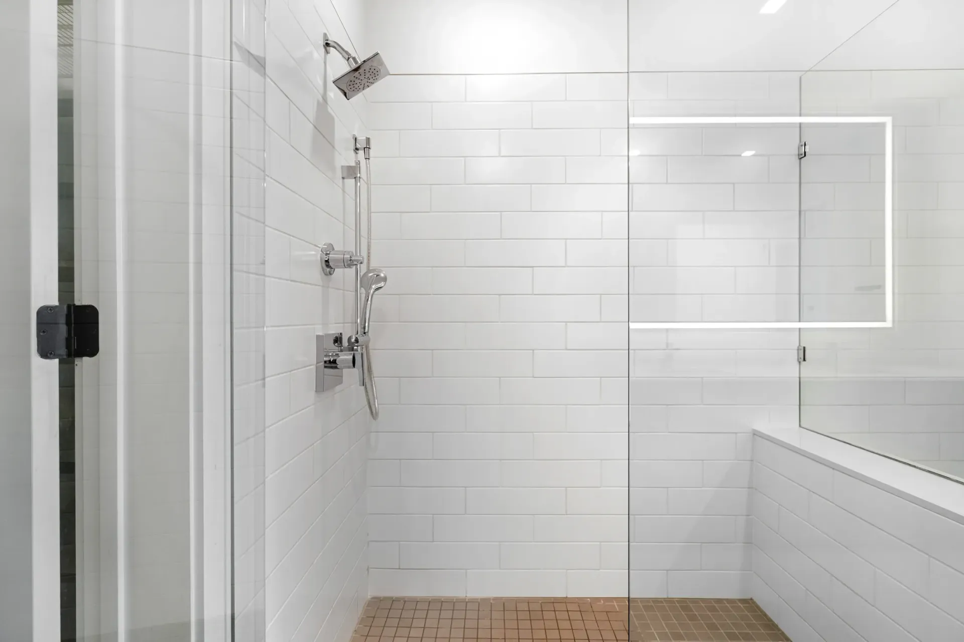 Modern walk-in shower with white subway tile and glass door.