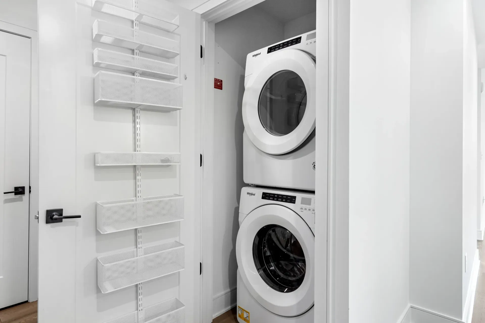 Stackable washer and dryer in a laundry closet with ample shelving.