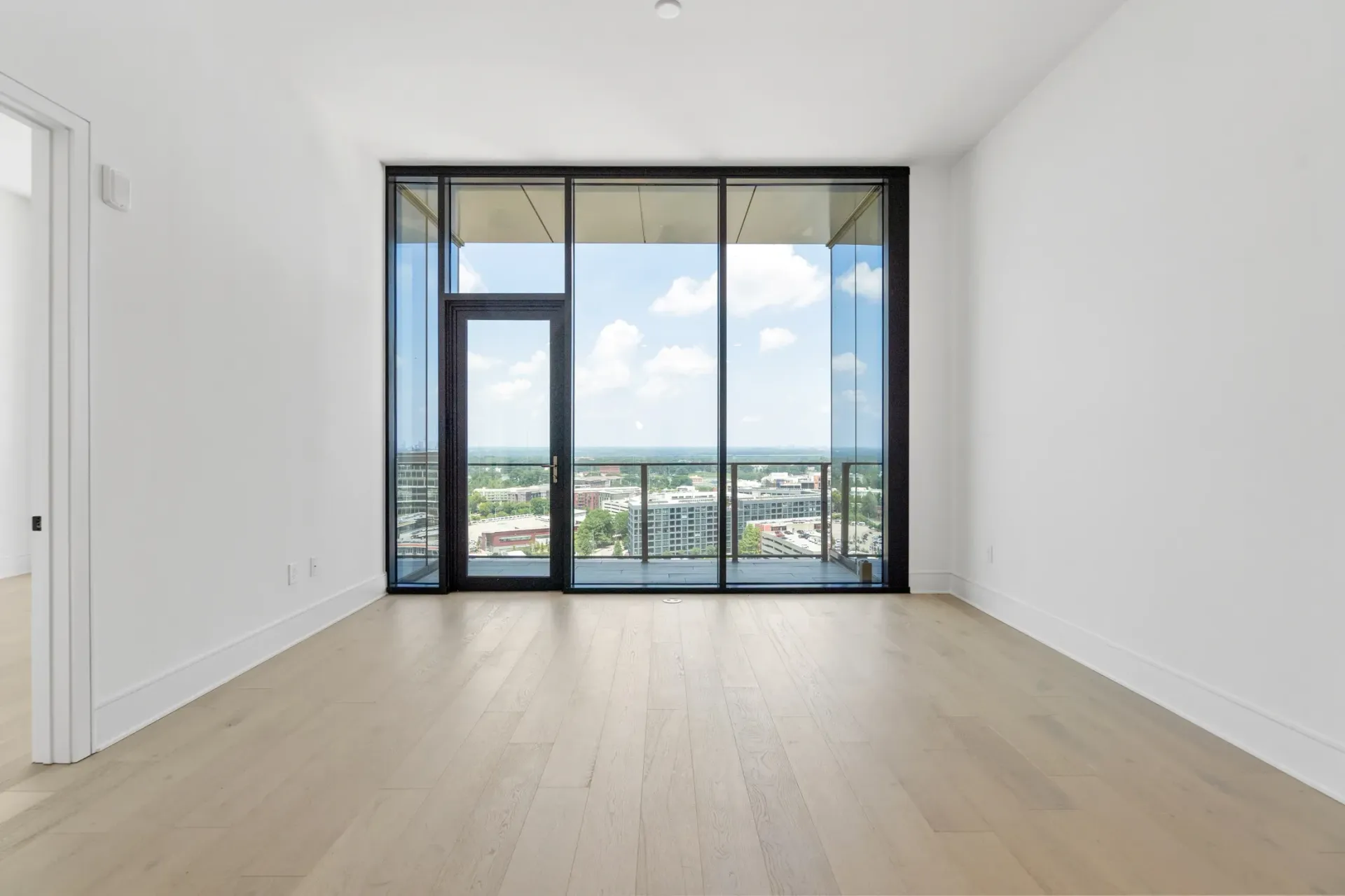 Interior view of an unfurnished apartment living room with large windows and a city view.