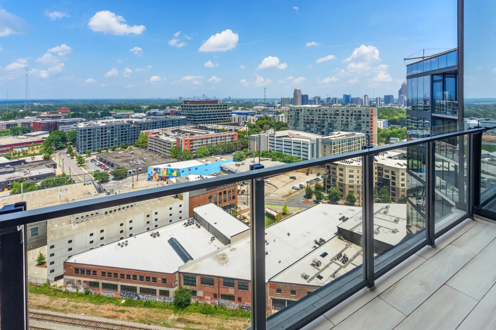 View of a city skyline from a balcony with glass railings.