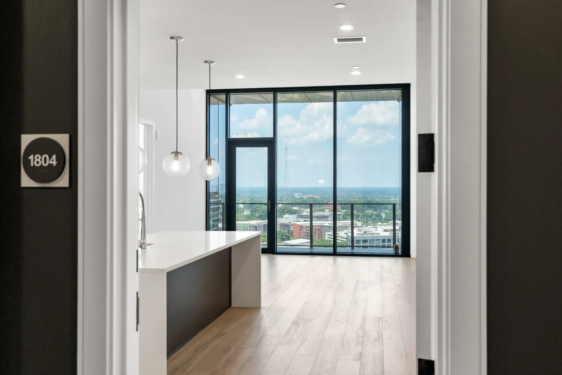 View from kitchen island to living room with floor-to-ceiling windows and city view.