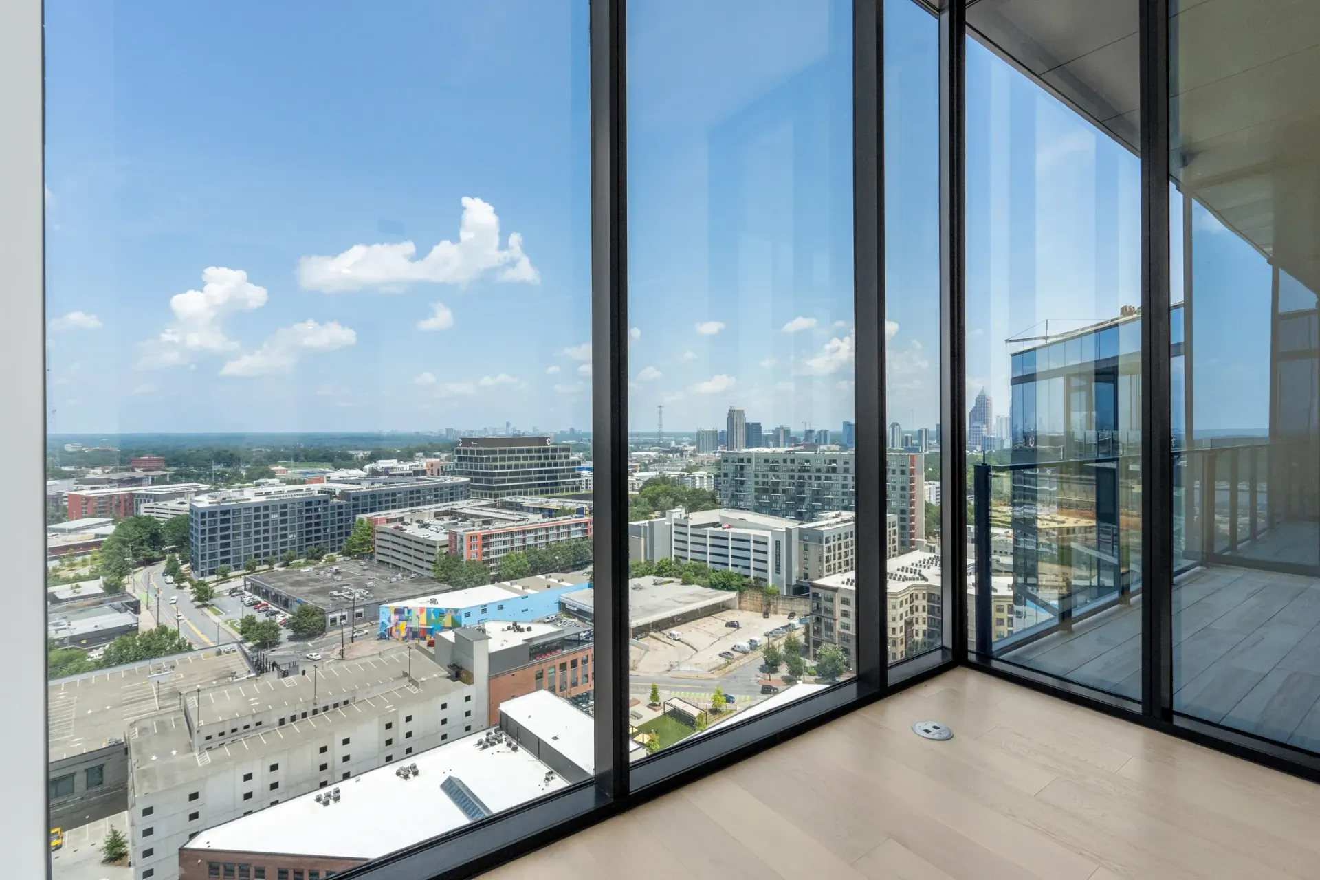 View from a high-rise apartment window overlooking a cityscape with modern buildings.
