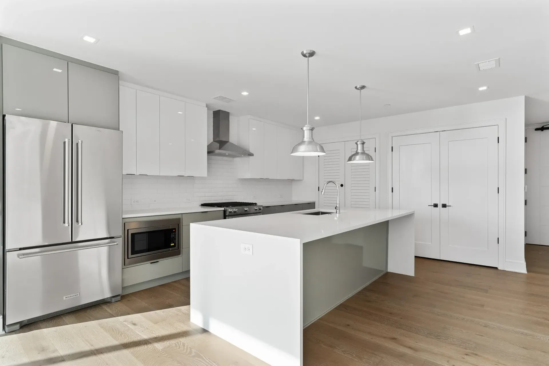 Modern kitchen with stainless steel appliances, white countertops, and island.