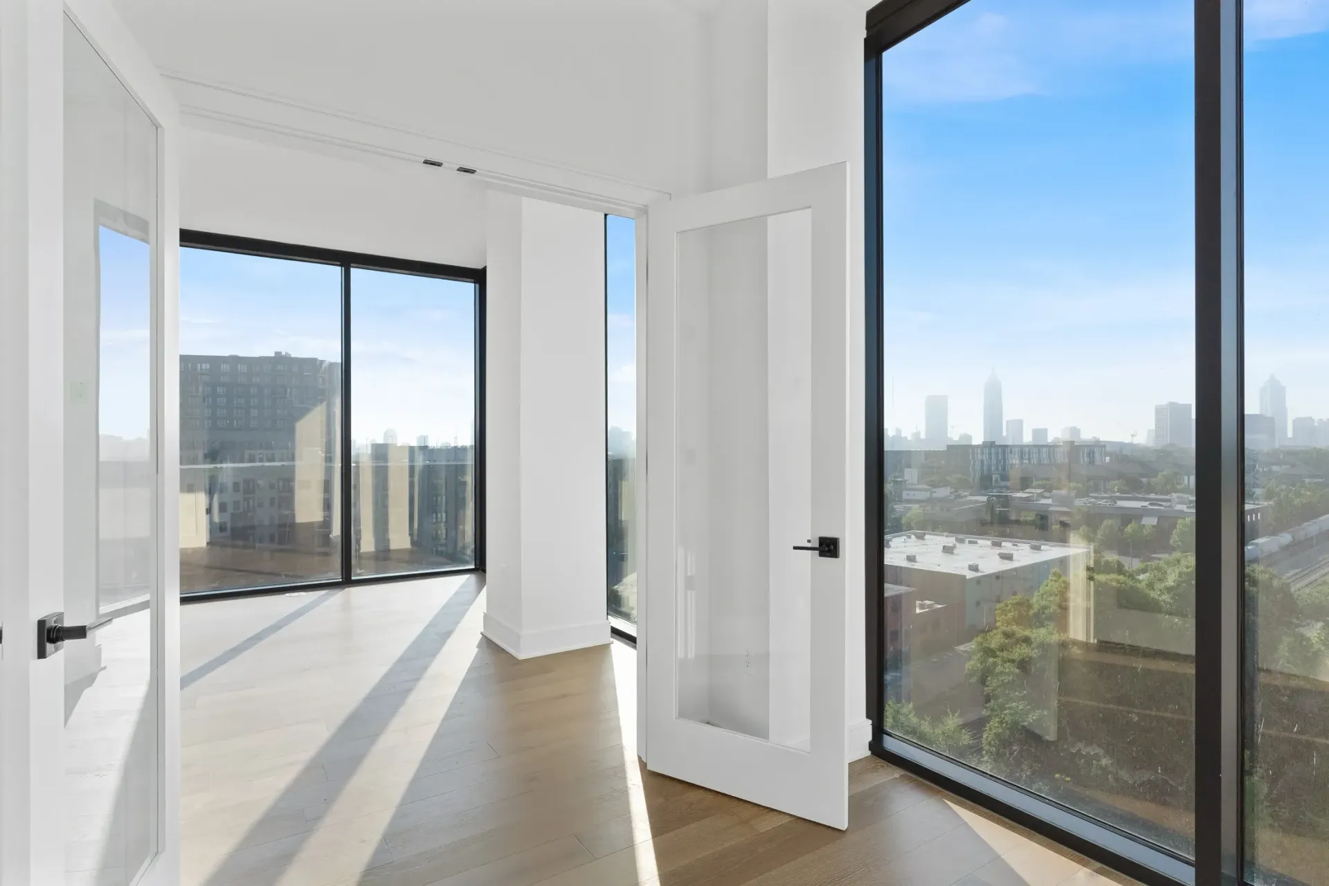 Interior view of a modern apartment with large windows overlooking a city skyline.