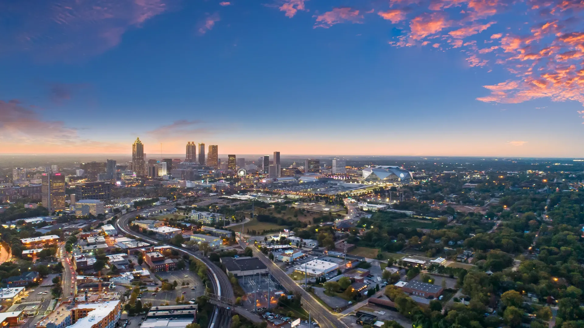 Aerial view of downtown Atlanta skyline at sunset with glowing clouds.