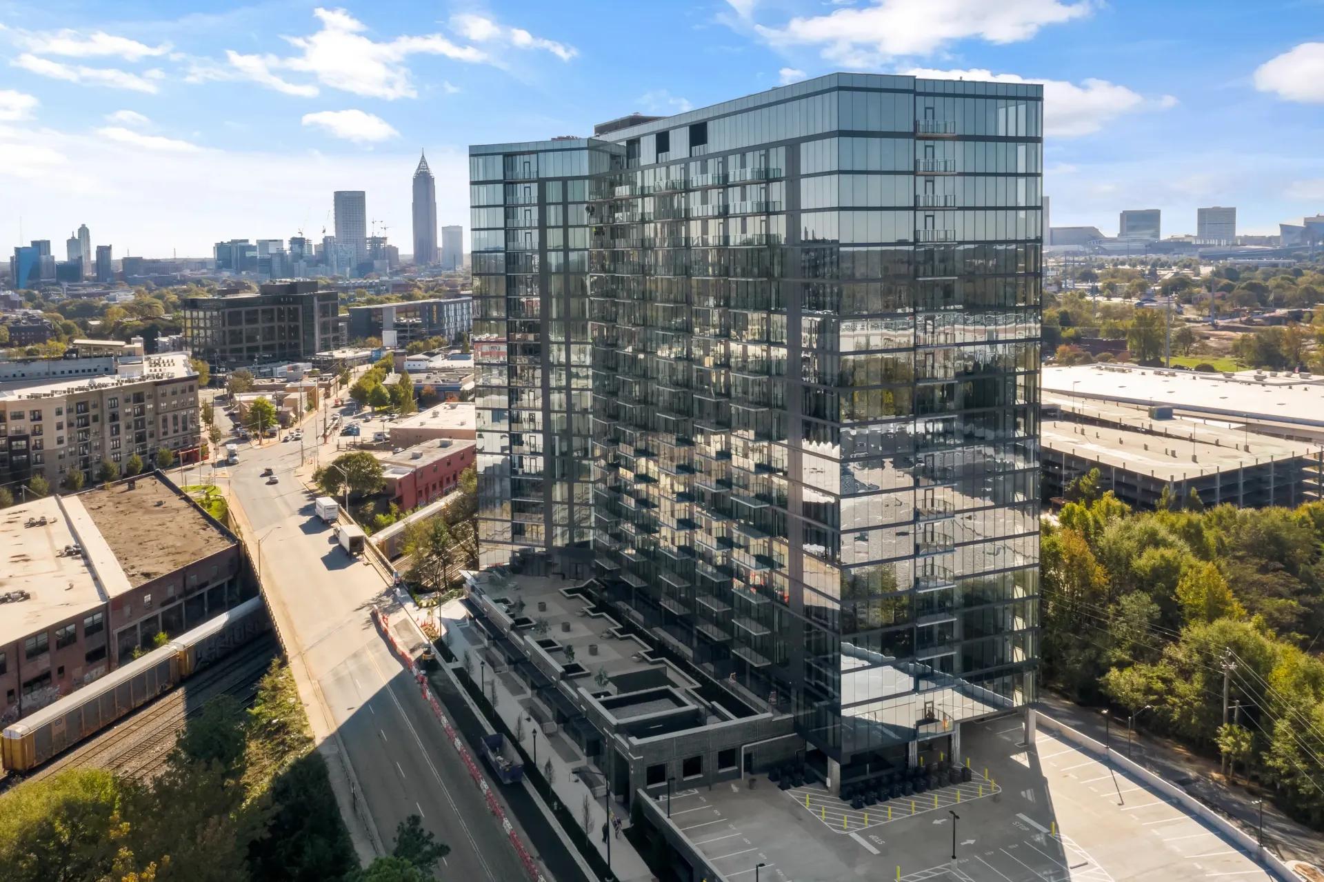 Modern glass apartment building exterior with city skyline in the background.