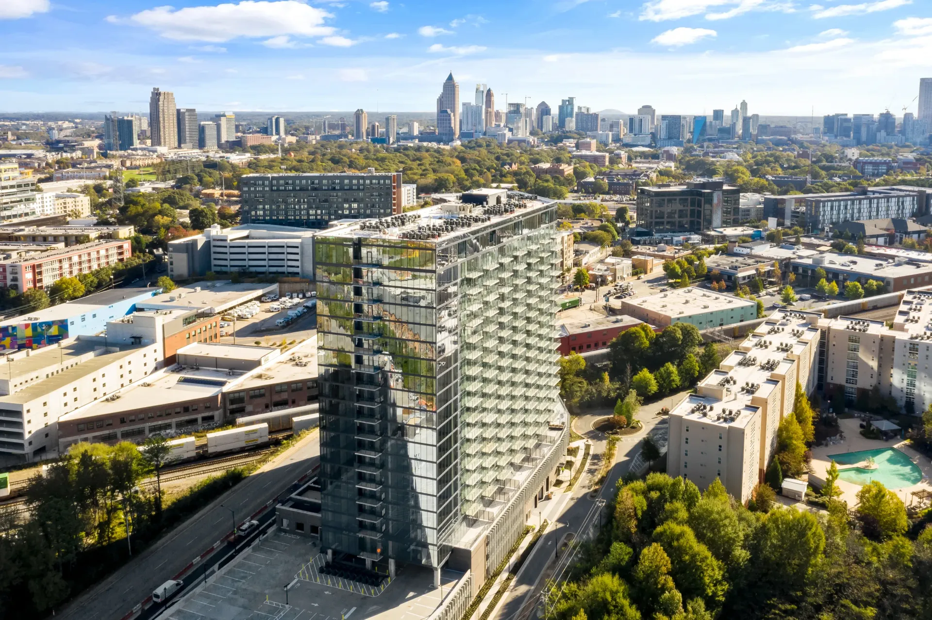 Aerial view of a modern glass apartment building with a cityscape in the background.