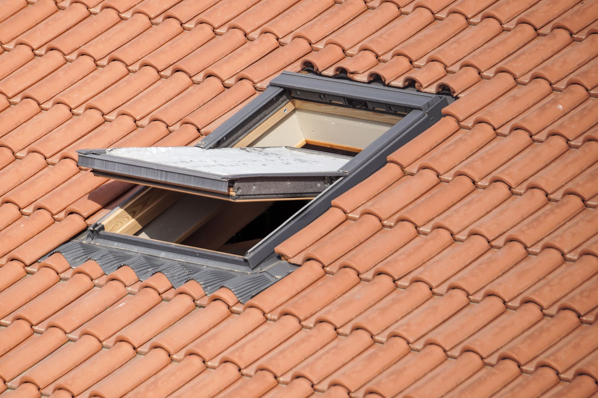 Open skylight on a terracotta tiled roof.