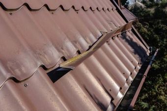 Brown metal roof with a bent flashing strip and gutter.