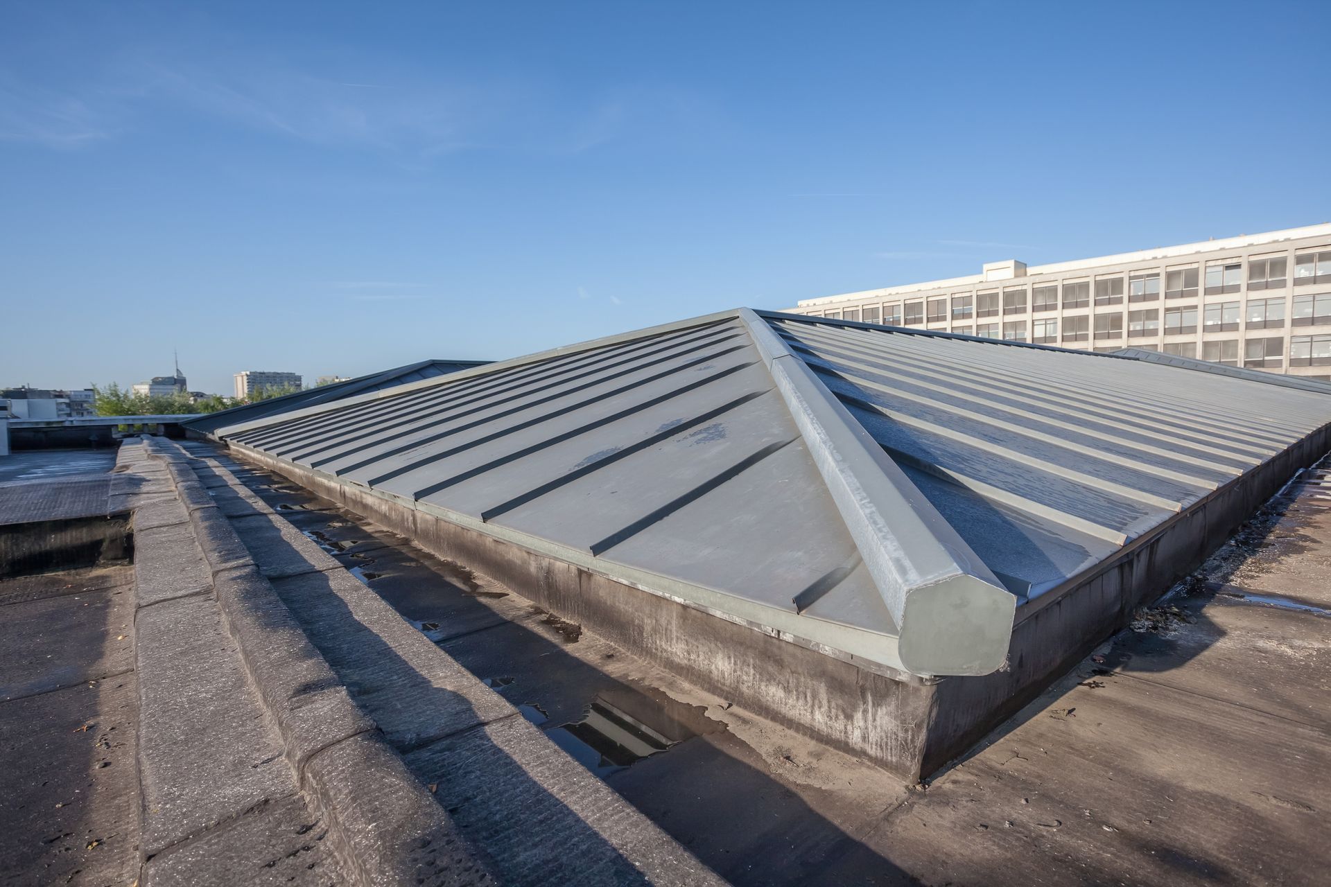 Gray metal roof with a skylight, blue sky.