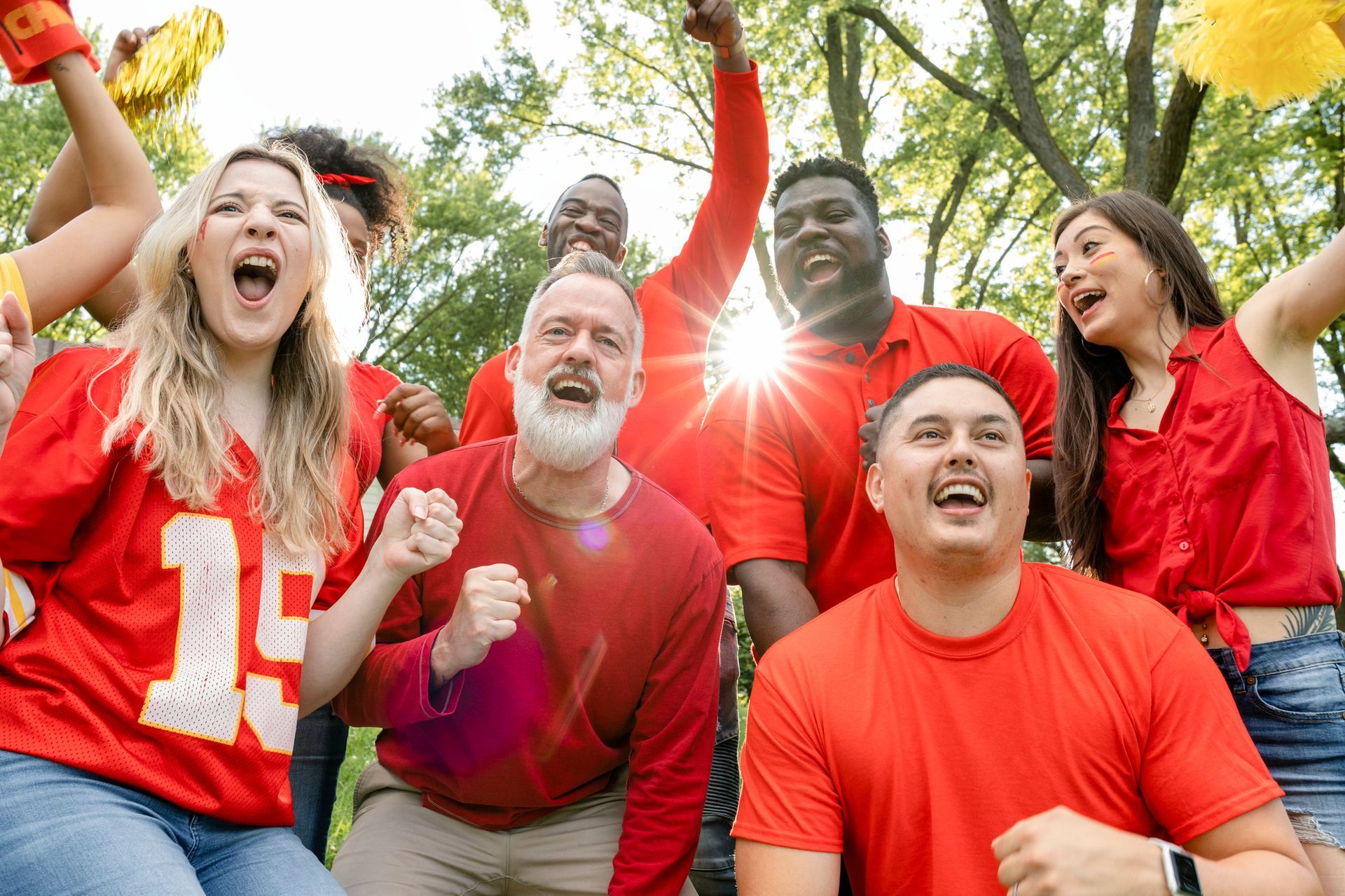 A group of people wearing red shirts are cheering for a football game.