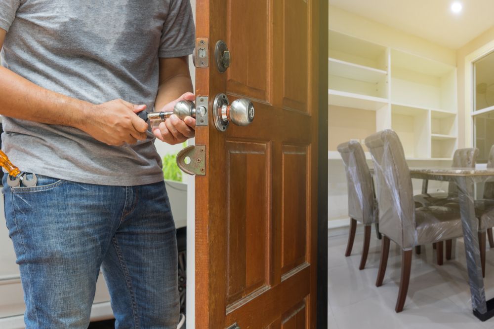 A Man is Fixing a Door Knob in a Dining Room — Eddie Williams Locksmiths in Palm Cove, QLD