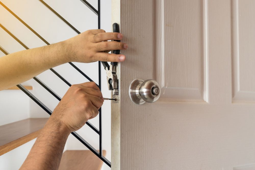 A Man Is Fixing A Door With A Screwdriver — Eddie Williams Locksmiths in Cairns City, QLD