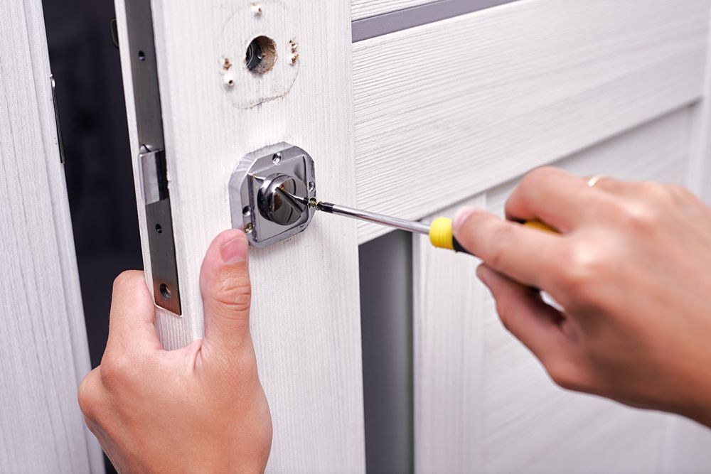 A Person is Fixing a Door Lock With a Screwdriver — Eddie Williams Locksmiths in Palm Cove, QLD