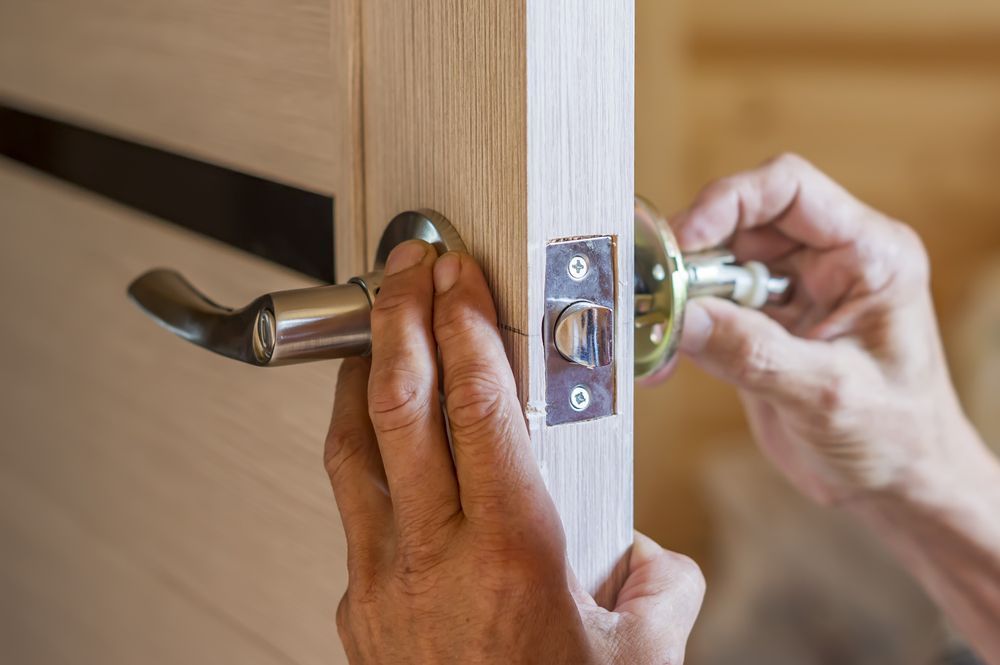 A Person is Installing a Door Handle on a Wooden Door — Eddie Williams Locksmiths in Palm Cove, QLD