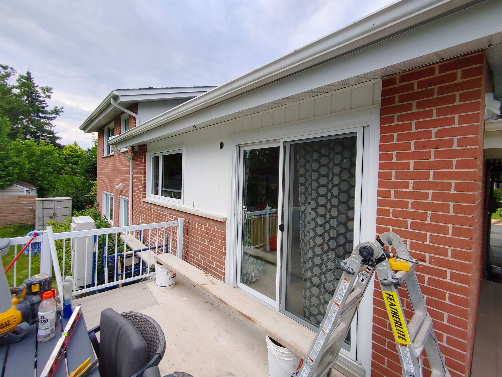 Une échelle est posée sur le côté d'une maison en briques.