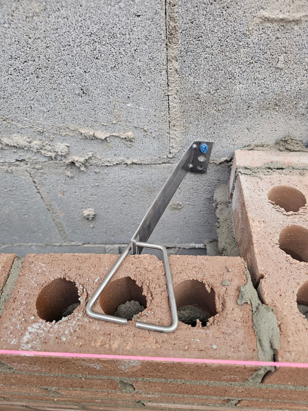 Un mur de briques est en train d'être construit avec des briques et un outil en métal.