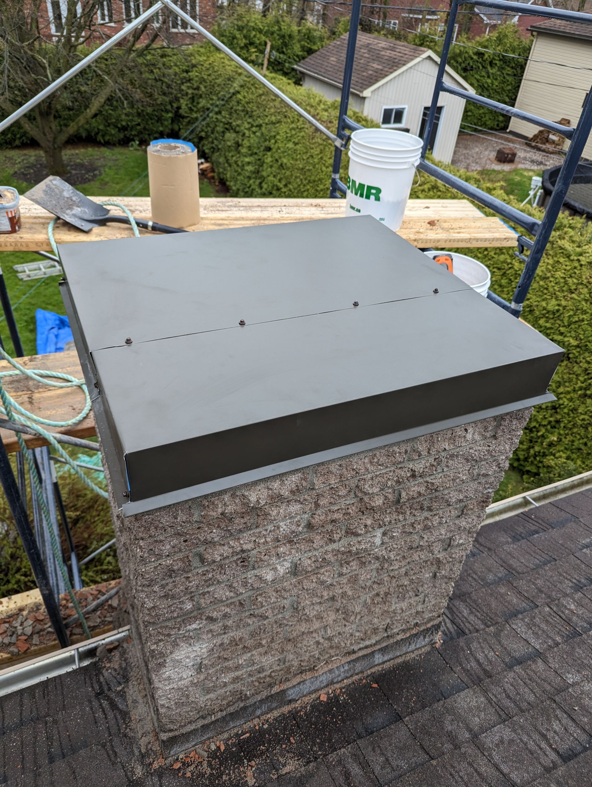 Une cheminée en béton est en cours de réparation sur un toit.