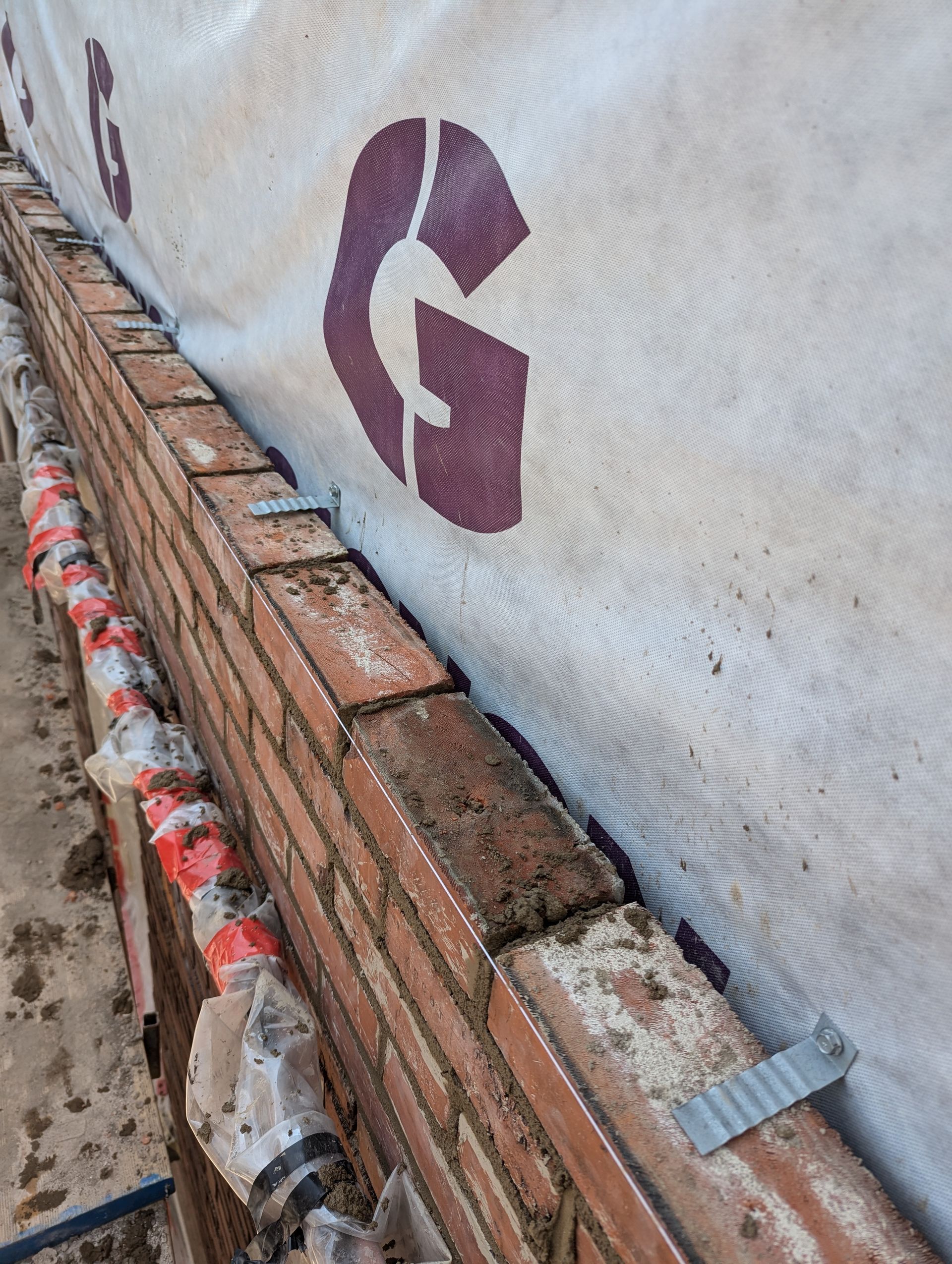 Un mur de briques avec un g au pochoir est en cours de construction.