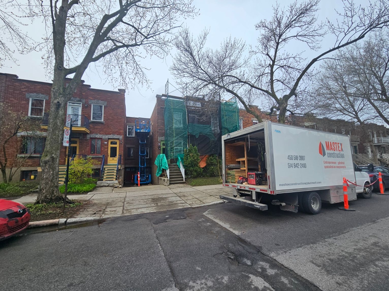 Un camion blanc est garé devant un bâtiment en briques.