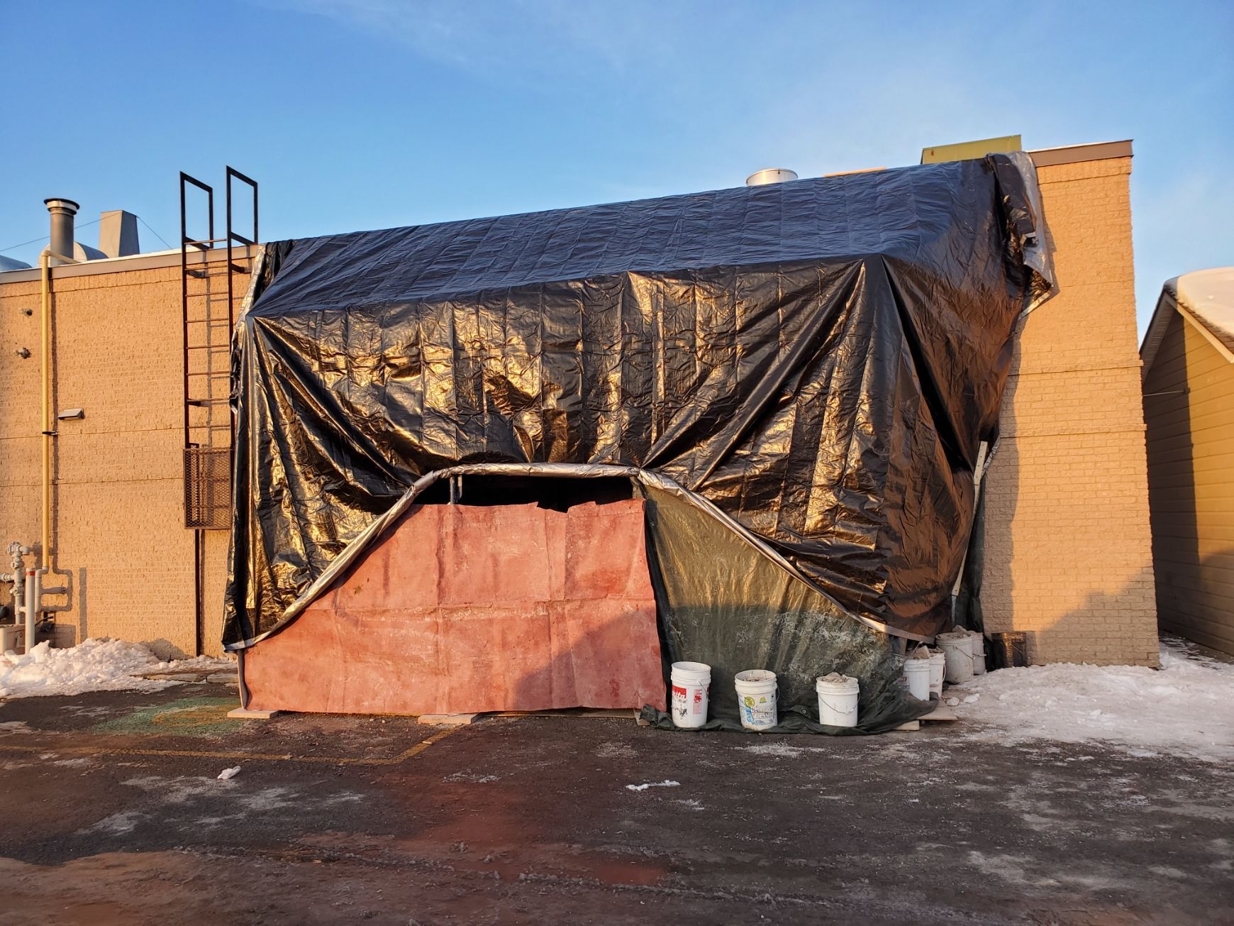 Un bâtiment avec une bâche dessus et des seaux devant
