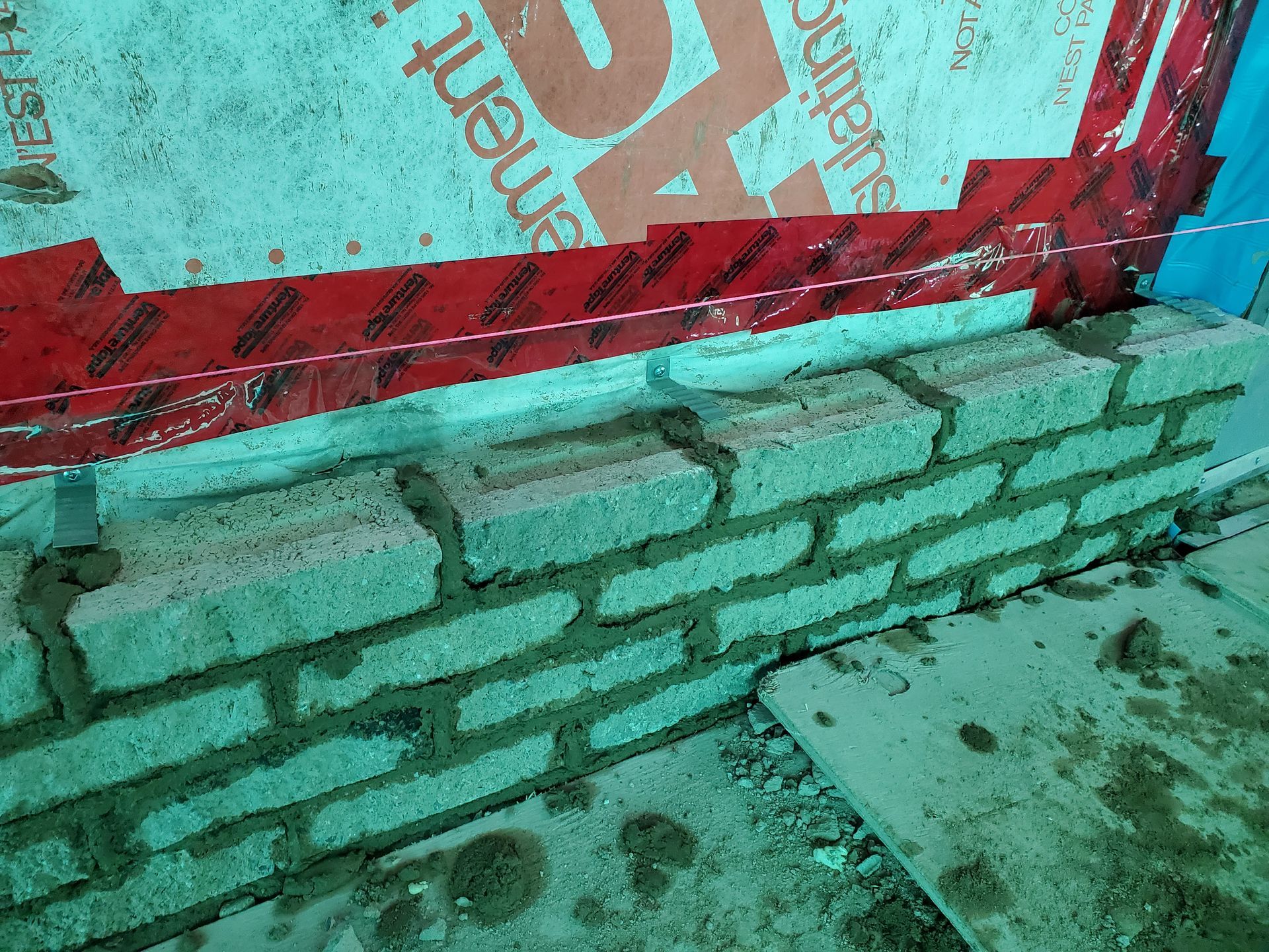 Un mur de briques est en train d'être construit avec un morceau de papier rouge et blanc qui le recouvre.