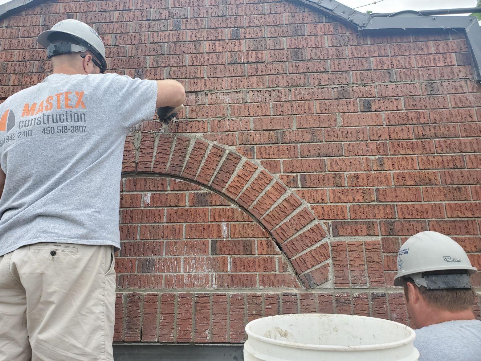 Un homme portant une chemise de maître en construction travaille sur un mur de briques