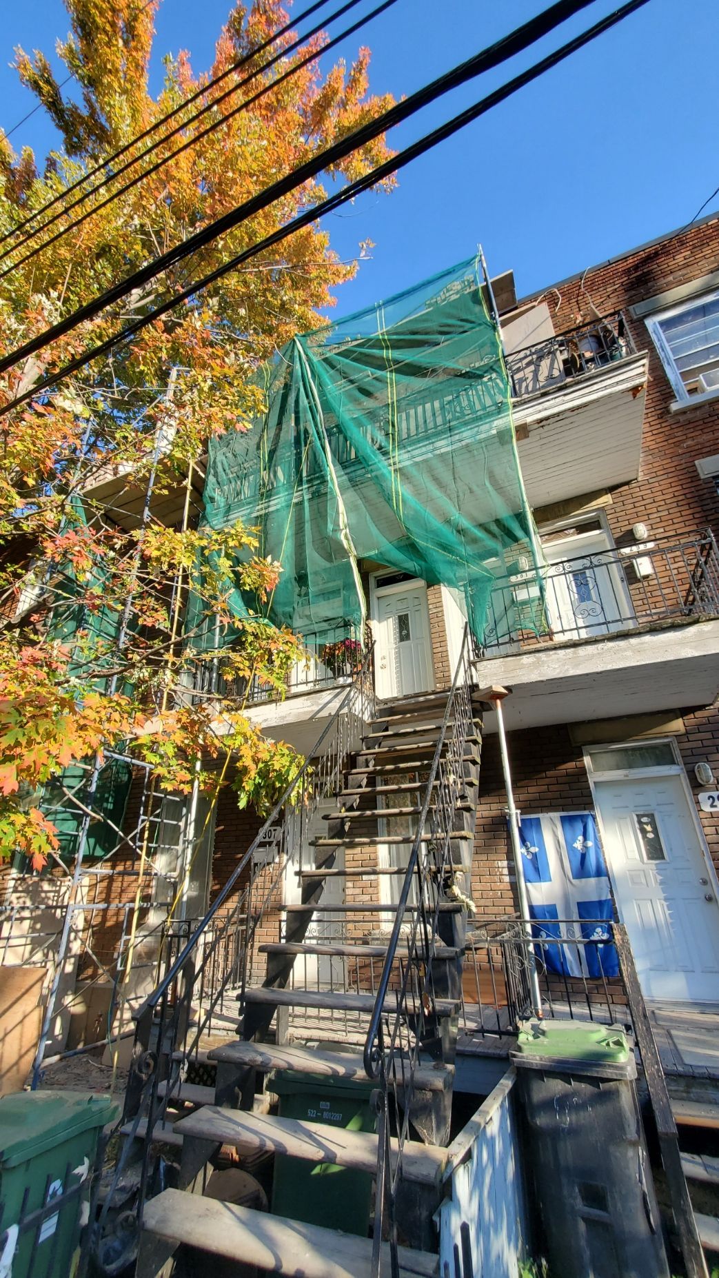 Un bâtiment avec des escaliers et une bâche verte dessus.