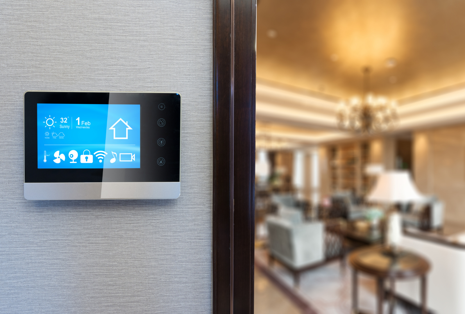 Wall-mounted blue touchscreen thermostat beside a doorway, with a softly lit living room in the background.