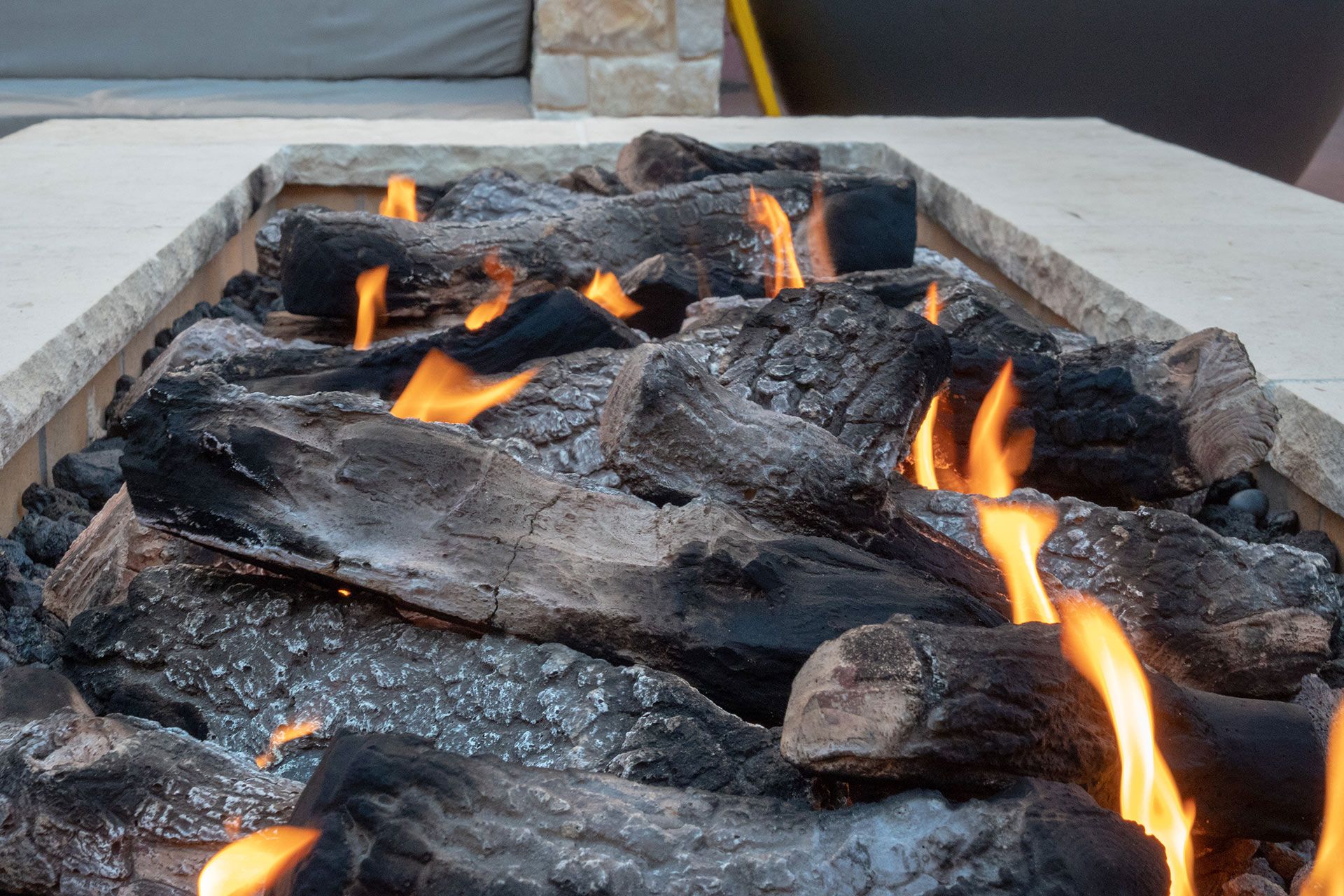 Fire pit with burning, charred logs and yellow flames.