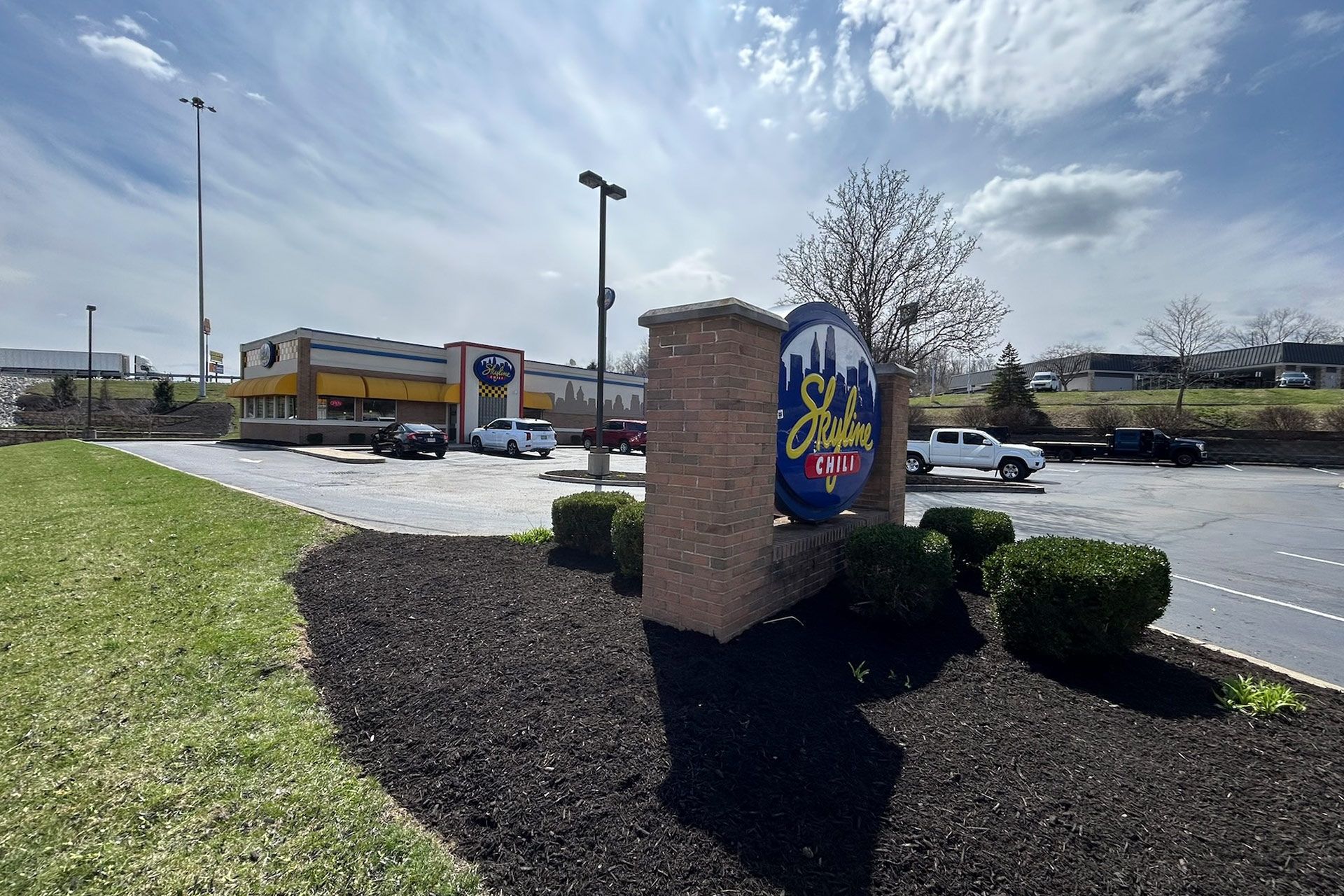 Sign for City Barbeque with building in background and cars parked nearby.