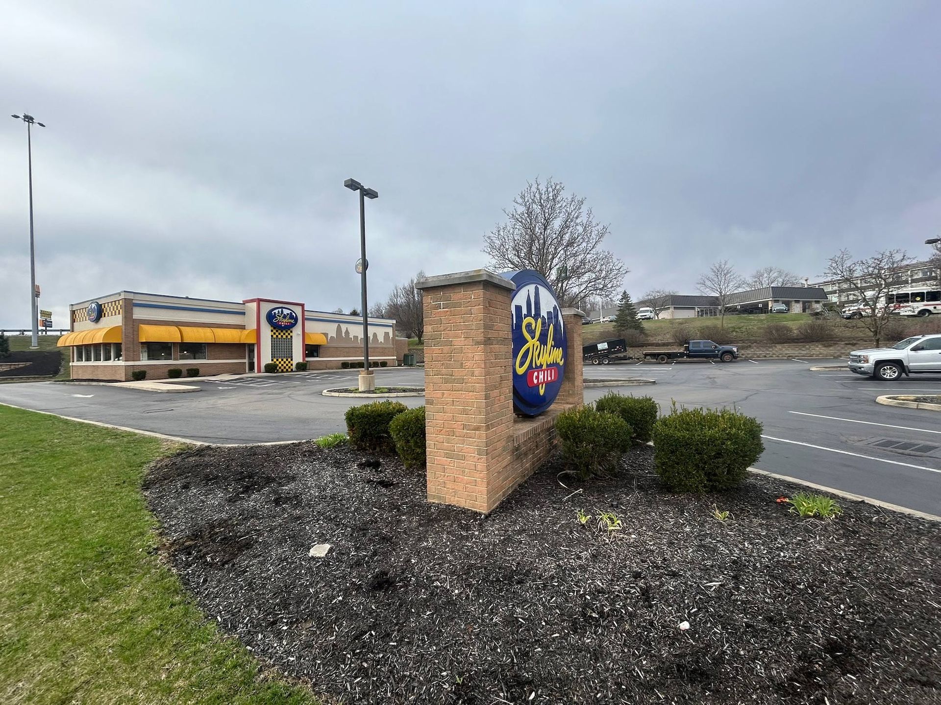 Restaurant sign and building with a cloudy sky. Brick sign with blue and yellow logo.