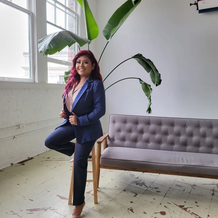 Yaret Lopez, dressed in a suit and is standing next to a couch