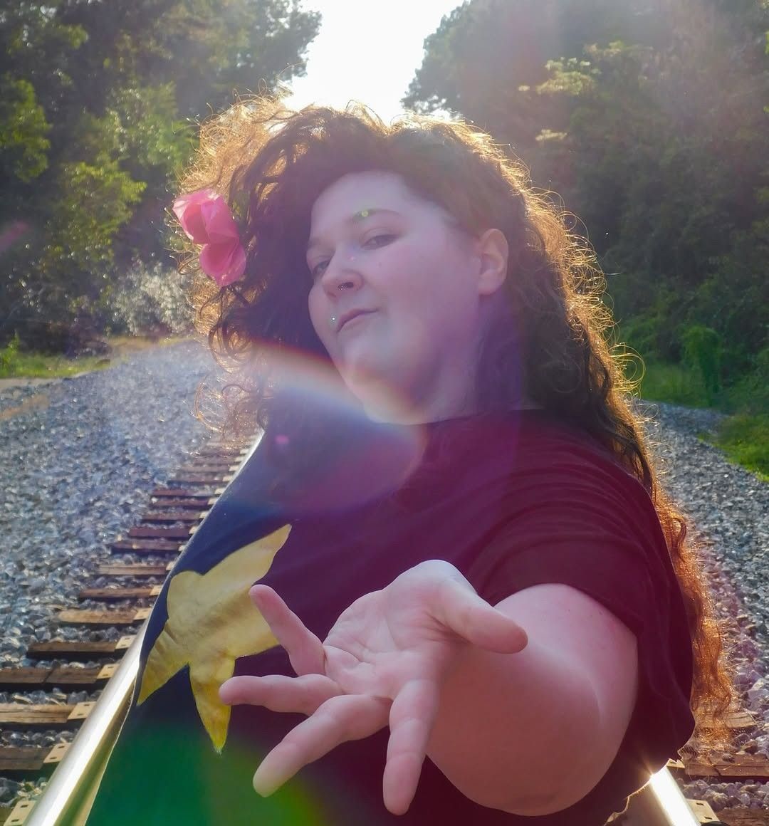 An image of a plus-size nonbinary person dressed as Greg Universe from Steven Universe.