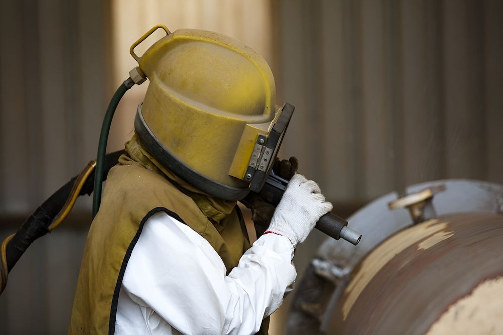 Worker in Protective Gear Sandblasting a Large Metal Object — Mudgee Powder Coat Pty Ltd in Mudgee, NSW