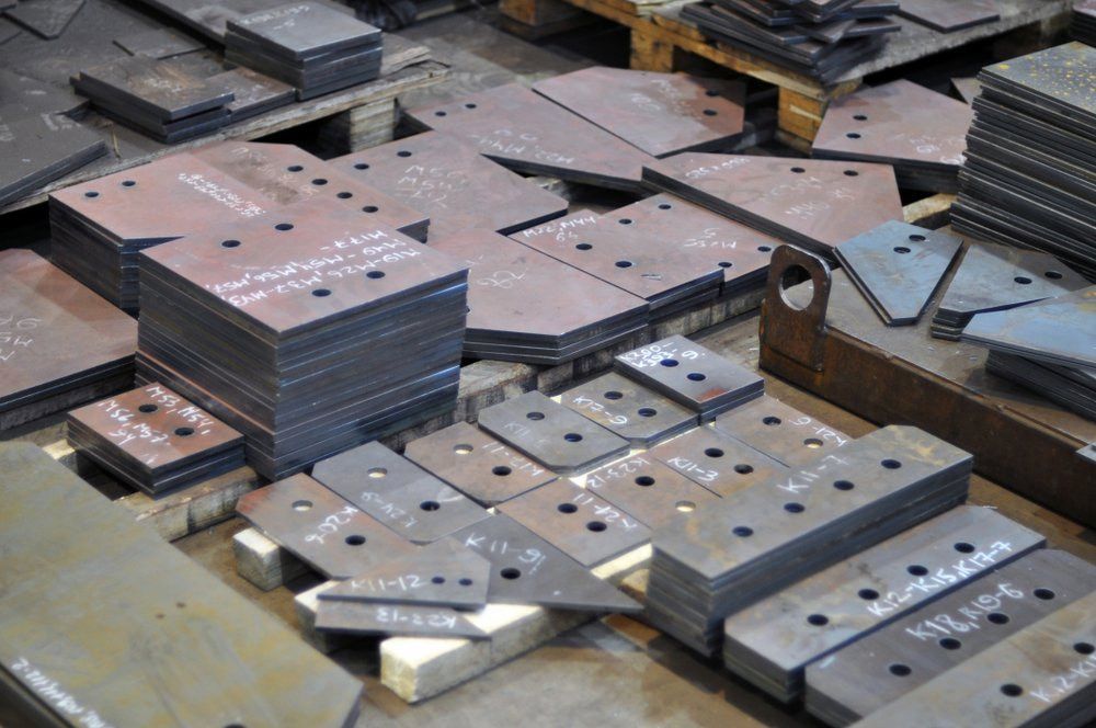 A Bunch of Metal Pieces Are Stacked on Top of Each Other on a Table — Mudgee Powder Coat Pty Ltd in Mudgee, NSW