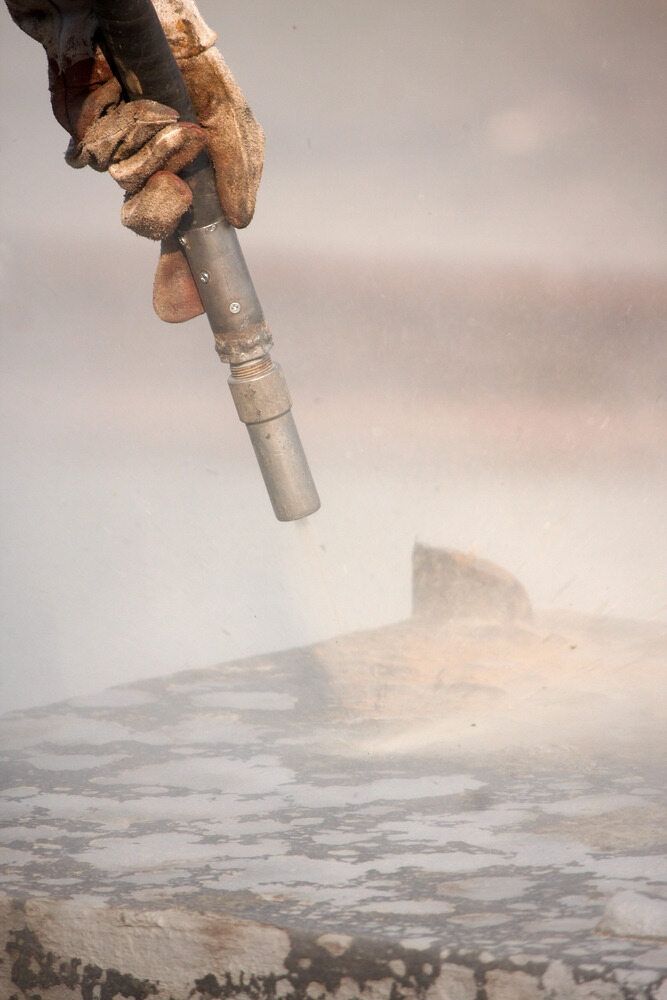 A Man Sandblasting a Piece of Metal — Mudgee Powder Coat Pty Ltd in Lithgow, NSW