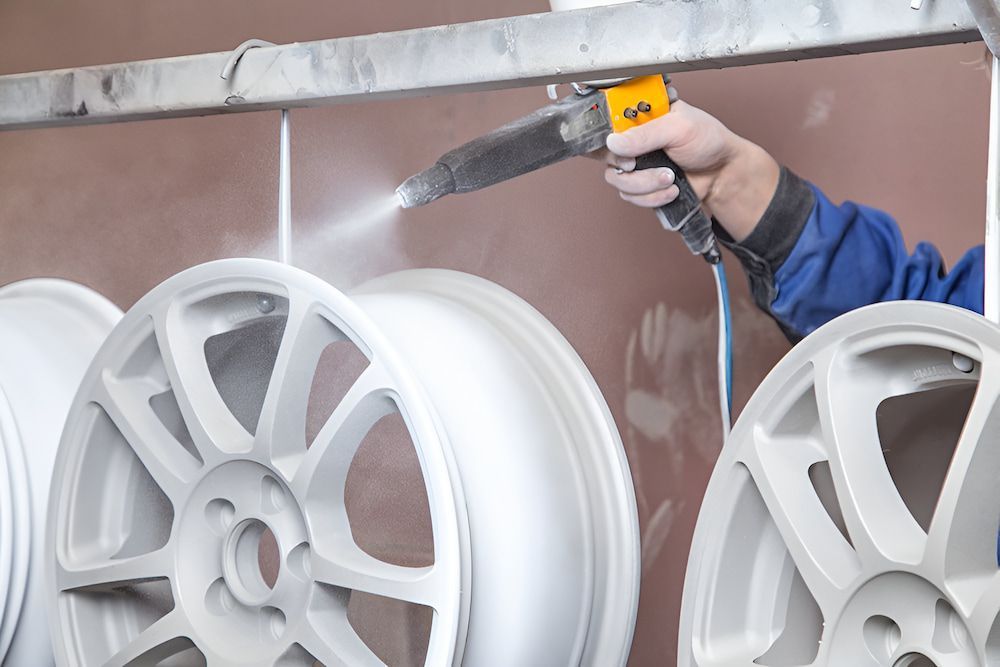 A Person is Spraying Powder on a Set of Wheels — Mudgee Powder Coat Pty Ltd in Mudgee, NSW