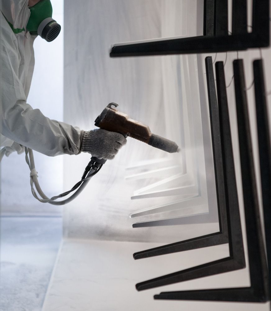 Worker Powder Coating Metal Chair Legs in a Booth — Mudgee Powder Coat Pty Ltd in Mudgee, NSW