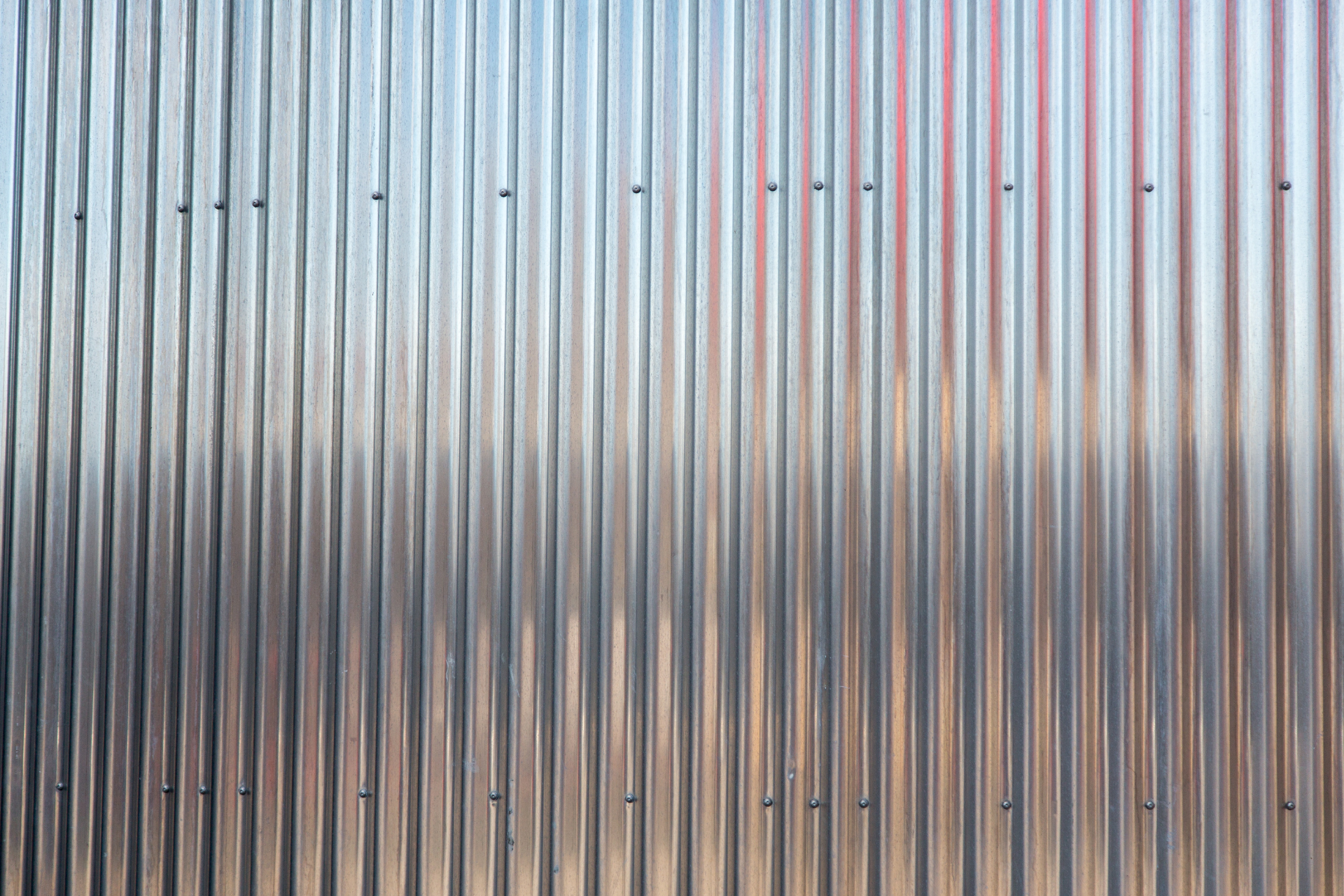 A close up of a metal wall with a reflection of a building in it.