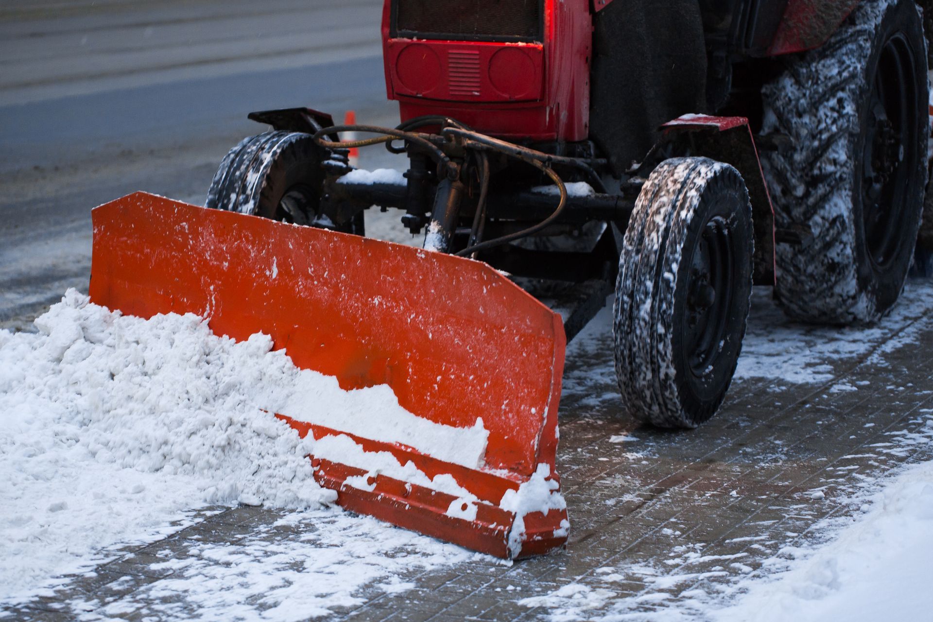 Red snowplow clearing snow from a street.