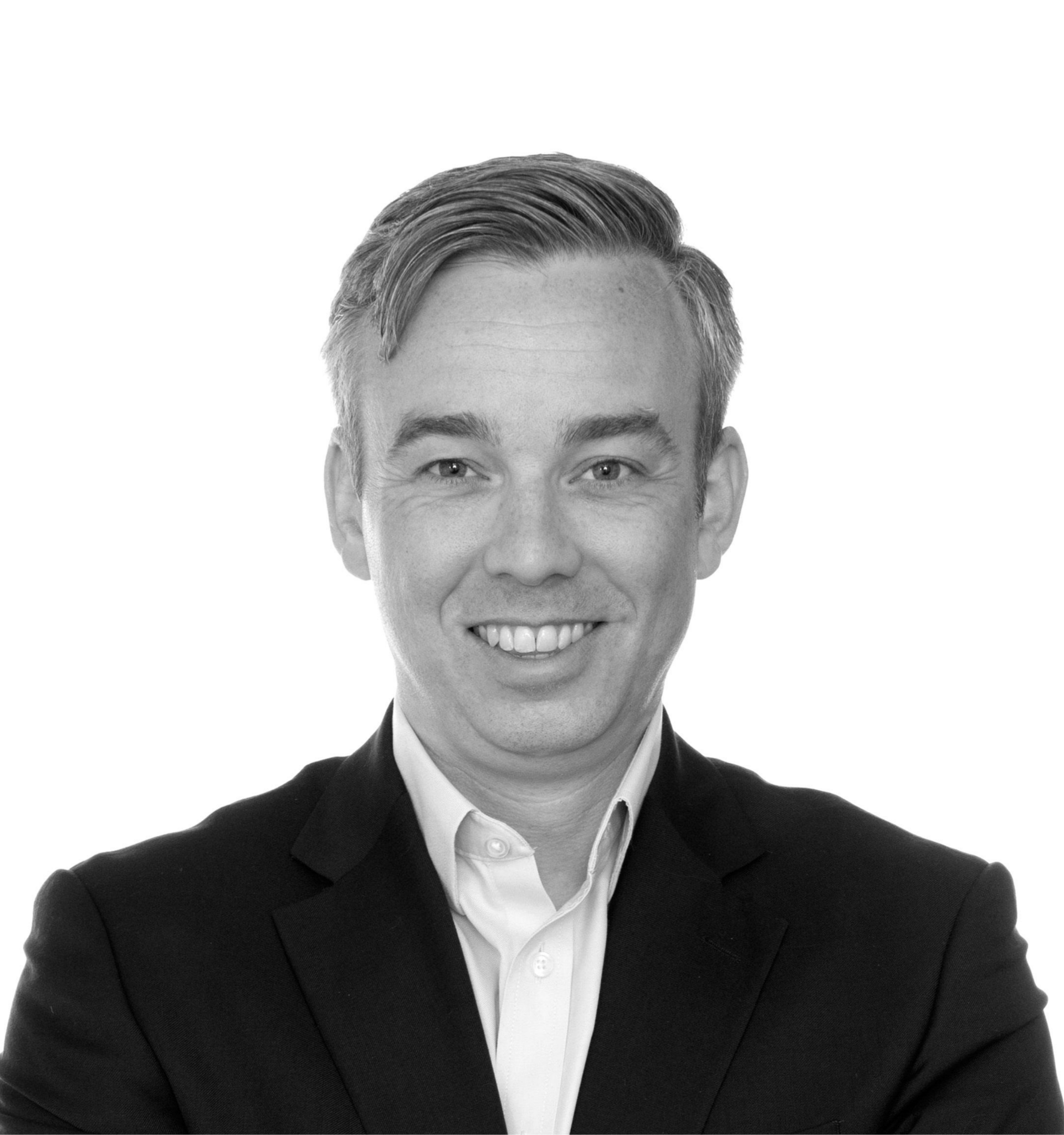 Man smiling, wearing a suit jacket and light-colored collared shirt, against a white background.