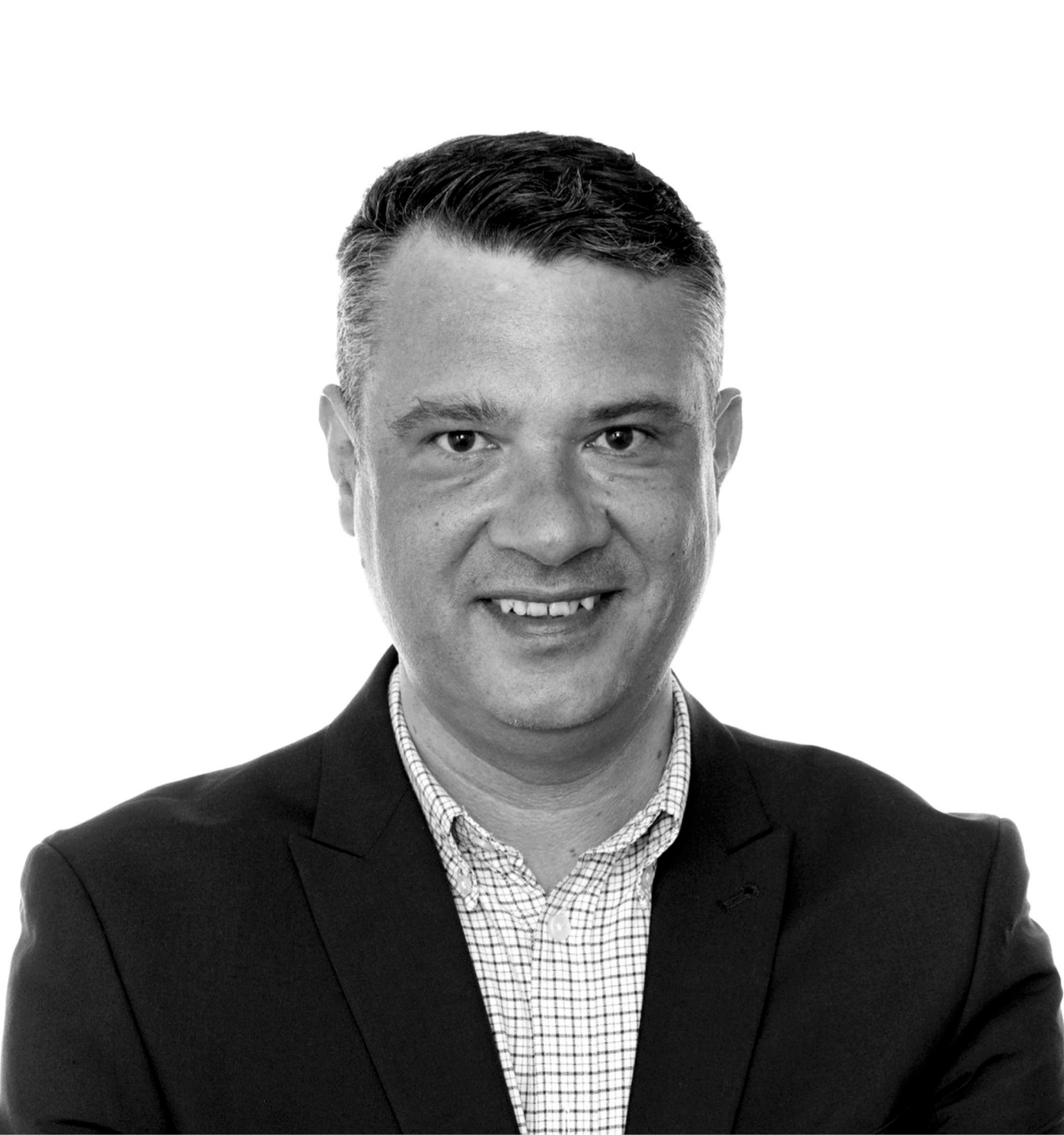 Man in blazer and patterned shirt smiling, head and shoulders.