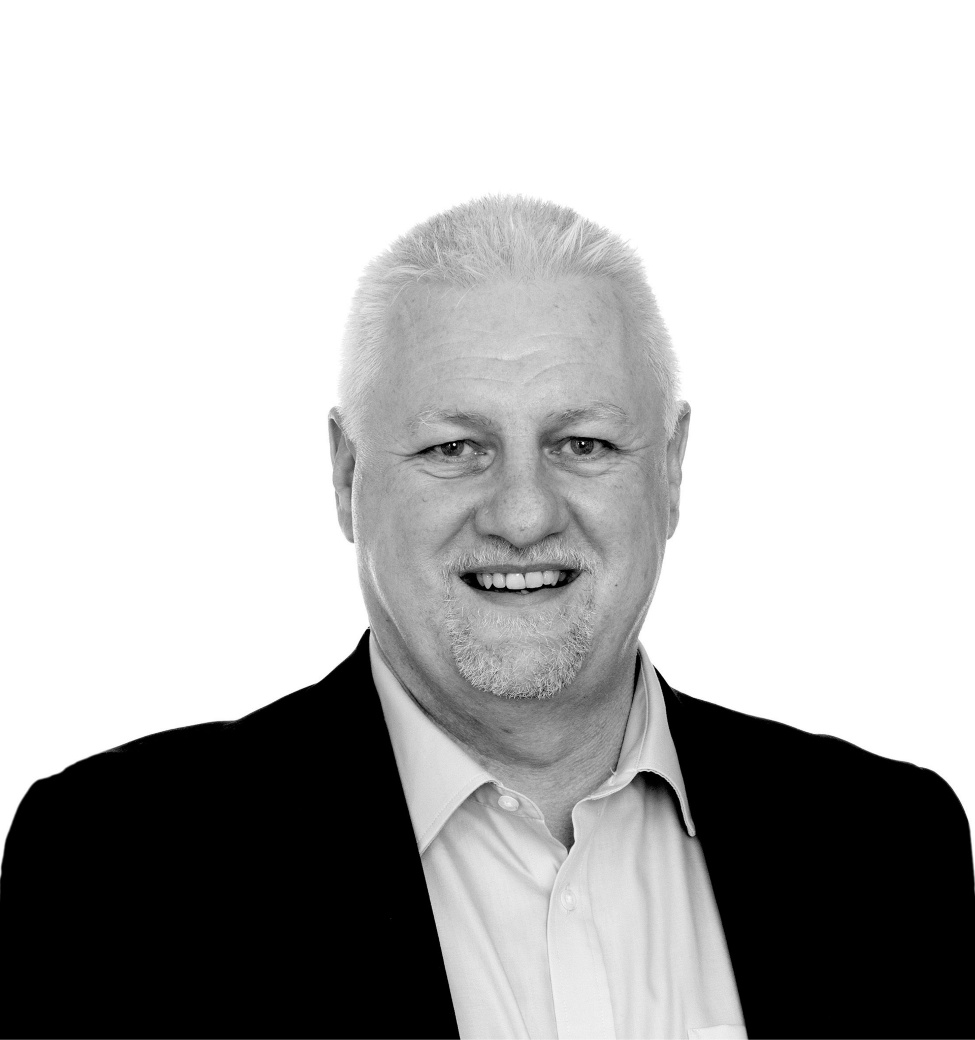 Smiling man in a suit jacket, light-colored shirt, and stubble.