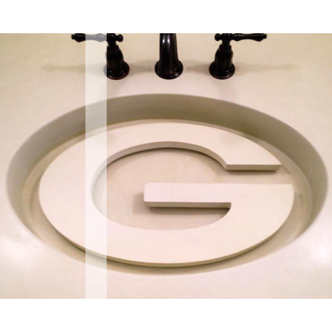 A concrete bathroom sink with the letter g carved into it.