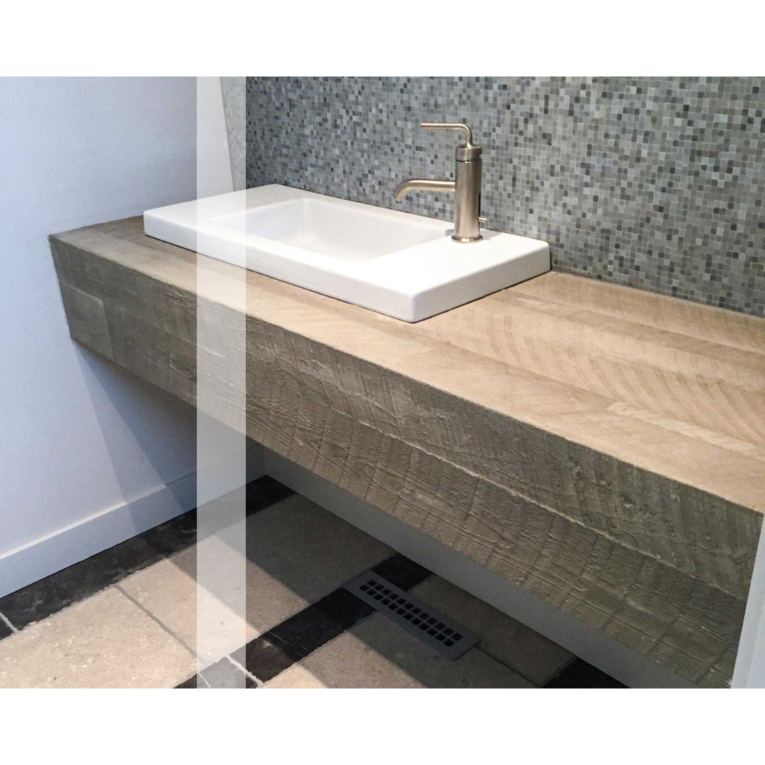 A concrete bathroom sink is sitting on top of a wooden counter.