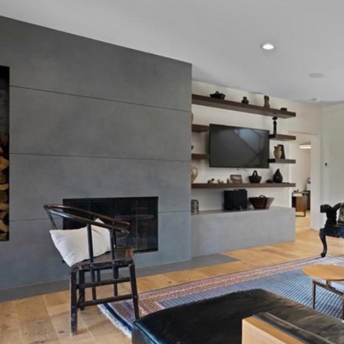 A living room with a concrete fireplace and a flat screen tv