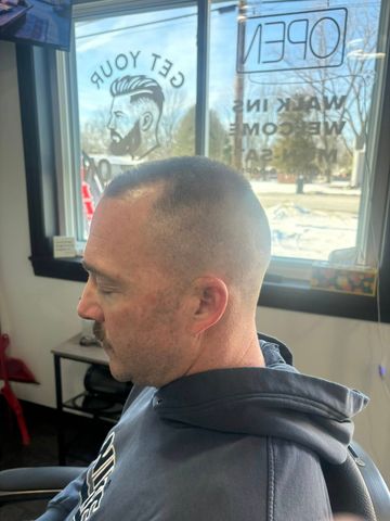 Man with a short haircut in a barber chair. A window with