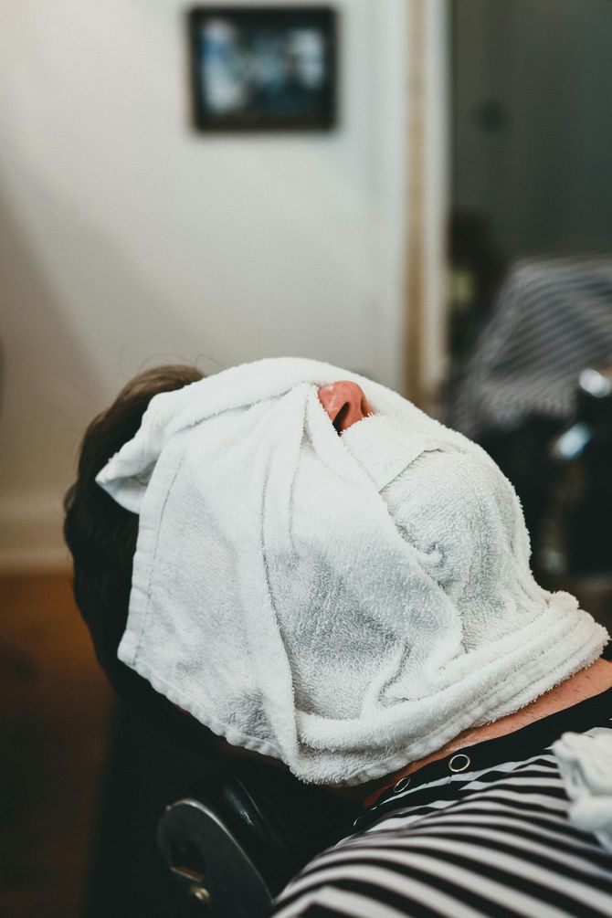 Woman getting her hair washed at a salon, face relaxed. Hands lather shampoo into her hair.